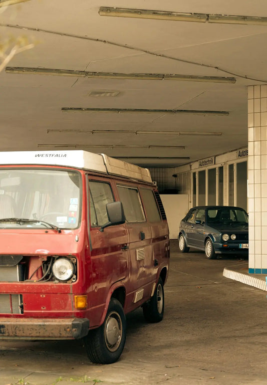 Red van and car parked under a covered area
